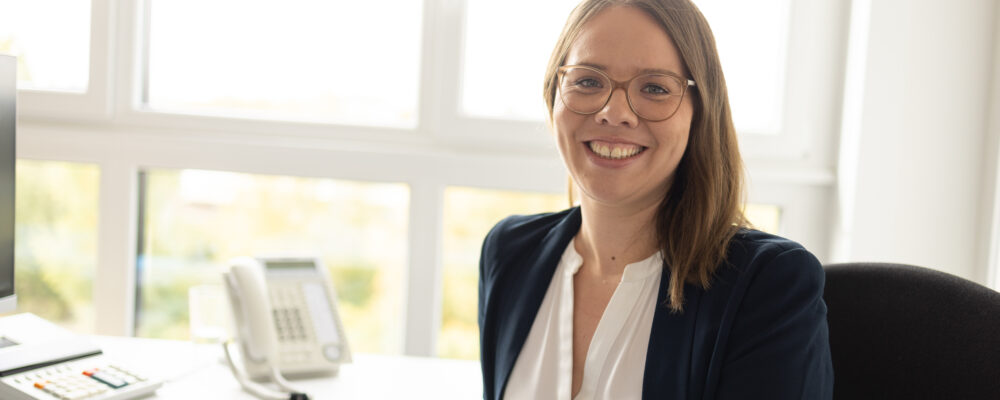 lächelnde Mitarbeiterin am Schreibtisch