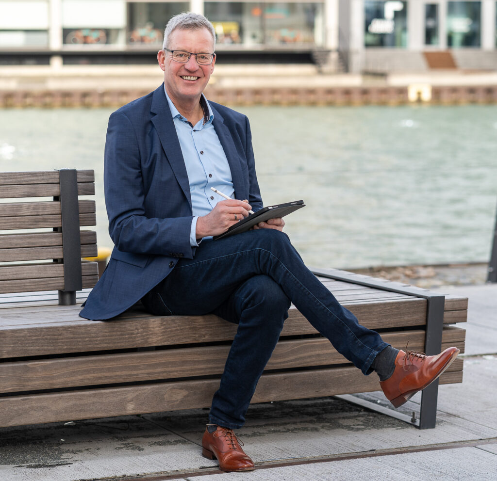 Klaus Panreck mit Tablet auf einer Bank sitzend